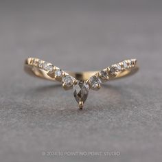 a yellow gold ring with two pear shaped diamonds on top and side stones in the middle