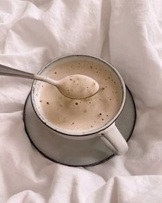 a cup of coffee with a spoon in it on a white cloth covered tablecloth