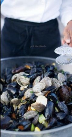 a person holding a spoon with clams in it