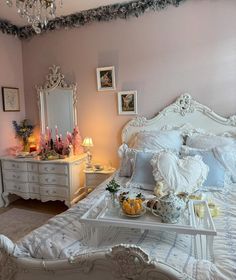 a white bed sitting in a bedroom next to a table with food on top of it