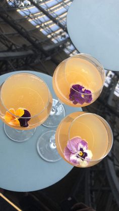 three glasses filled with drinks sitting on top of a table