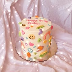 a white cake with colorful decorations on it sitting on top of a bed covered in stars