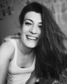 a black and white photo of a woman with long brown hair smiling at the camera