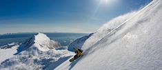 a snowboarder going down the side of a snowy mountain