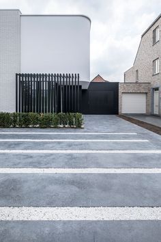 an empty parking lot in front of a white brick building with black fencing on it