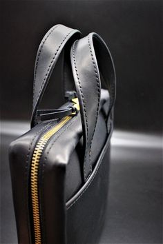 a black bag with gold zippers on the inside is shown in close up view