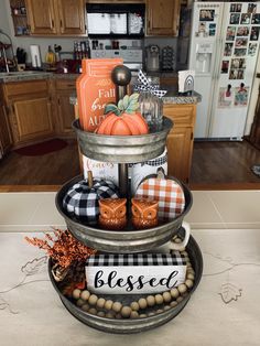 a three tiered tray with pumpkins and other items on it in a kitchen