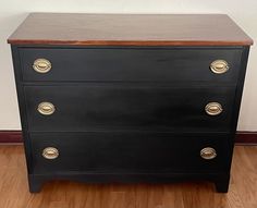 a black dresser with brass handles and wood top