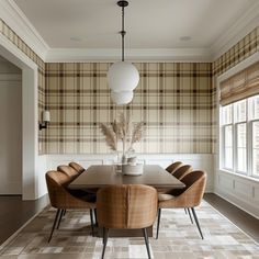 a dining room with plaid wallpaper and leather chairs in front of a large table