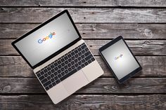 an open laptop computer sitting on top of a wooden table next to a smart phone