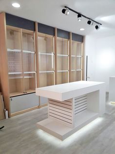 an empty room with shelves and lights on the ceiling, in front of a white counter