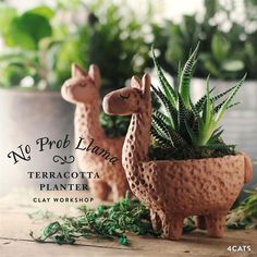 two clay llama planters sitting on top of a wooden table next to plants