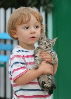 a little boy holding a cat in his arms