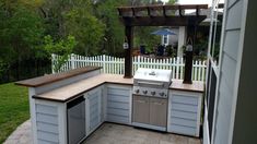 an outdoor kitchen is built into the side of a house with a grill and sink