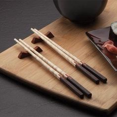 chopsticks and sushi on a wooden cutting board