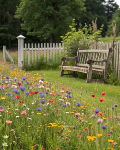 a wooden bench sitting in the middle of a lush green field filled with wildflowers