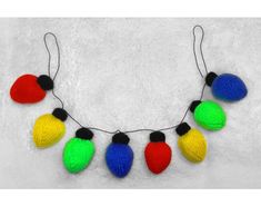 multicolored knitted christmas lights are hanging from a string on a white background