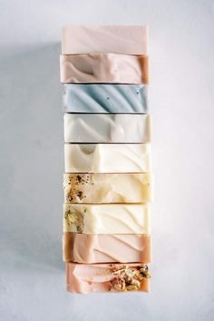 four bars of soap sitting on top of each other in different colors and shapes,