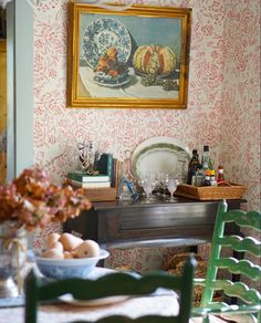 a painting hangs above a dining room table with dishes and glasses on it, next to a bowl of eggs