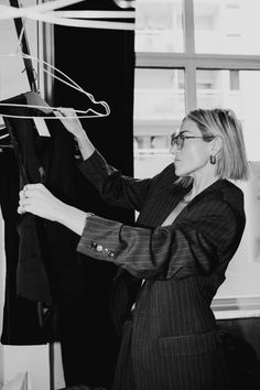 black and white photograph of woman looking at clothes on hangers