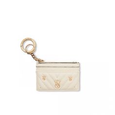 a small white purse with a gold keychain hanging from it's side