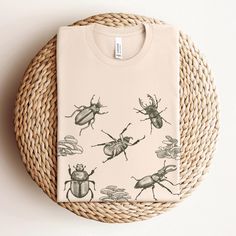 a t - shirt with bugs on it sitting on top of a woven wicker basket