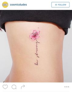 a woman's stomach with a pink flower tattoo on her left side ribcage