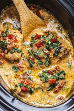 a wooden spoon in a slow cooker filled with chicken and spinach