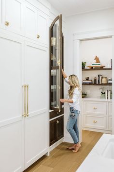 a woman is trying to open the door of her kitchen cabinet in order to get something fresh