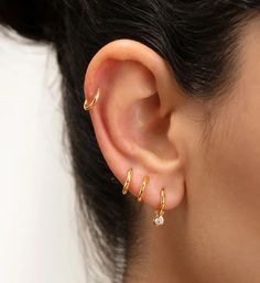 a close up of a person's ear with two small gold rings on it