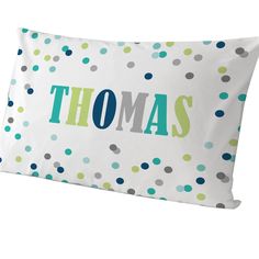 a pillow that says thomas on it with green and blue polka dot pattern in the background