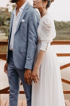 a man and woman standing next to each other in front of a body of water