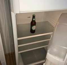 a beer bottle is sitting in an empty refrigerator