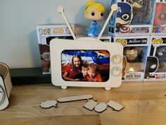 an old tv sitting on top of a wooden table next to some toy figurines