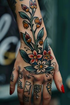 a woman's hand with tattoos and flowers on it