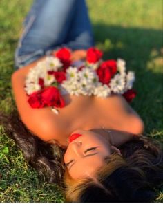 a woman laying on the grass with flowers in her hair