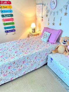 a bed with a teddy bear sitting on top of it next to a night stand