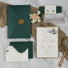 the wedding stationery is laid out on top of the marble table with flowers and greenery