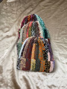 three multicolored knitted hats laying on top of a bed