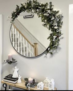 a round mirror hanging on the wall above a table with candles and other decorations in front of it