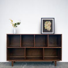 a vase with flowers sitting on top of a wooden shelf