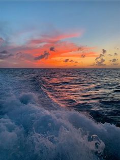 the sun is setting over the ocean as seen from a boat