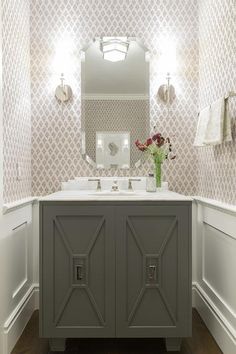 a bathroom with white walls and grey cabinetry in the center, along with a mirror on the wall