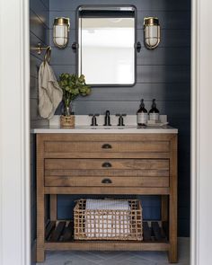 a bathroom with blue walls and white tile on the floor, along with a wooden vanity topped with a mirror