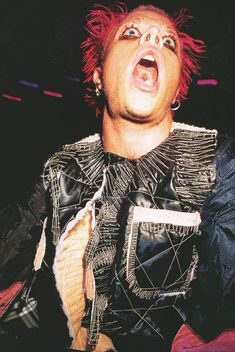 a man with red hair is singing into a microphone