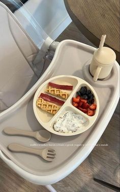 a tray with some food on it sitting on a chair next to a cup and fork