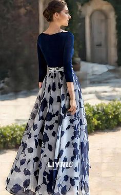 a woman in a blue and white dress is standing on the sidewalk with her back to the camera