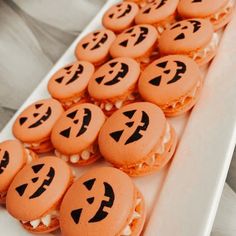 a white plate topped with lots of cookies covered in frosting and jack - o'- lantern faces