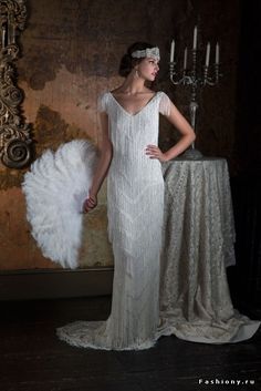 a woman in a white dress standing next to a table with an angel wings on it