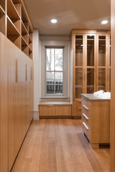 an empty walk in closet with wooden cabinets and drawers on either side of the window